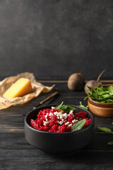 Bowl with tasty beet risotto on dark wooden background