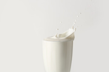 Glass of tasty milk with splashes on white background