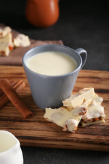 Cup with hot white chocolate on dark background