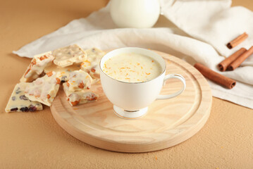 Cup with hot white chocolate on color background