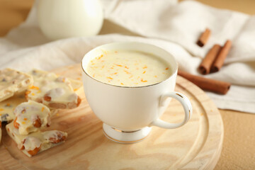 Cup with hot white chocolate on wooden background, closeup