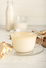 Cup with hot white chocolate on light wooden background
