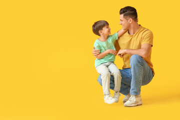 Happy father and his little son on color background