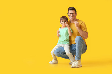 Happy father and his little son with party decor on color background