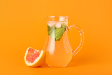 Jug of tasty grapefruit lemonade on color background
