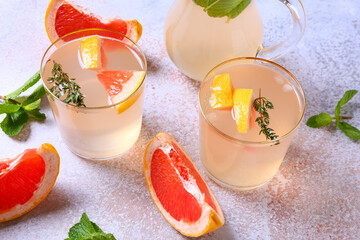 Glasses of tasty grapefruit lemonade on light background