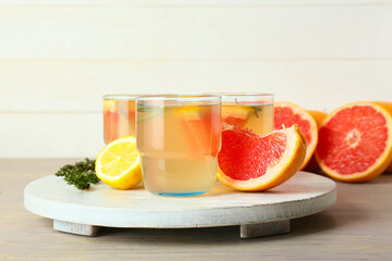 Glasses of tasty grapefruit lemonade on light wooden background