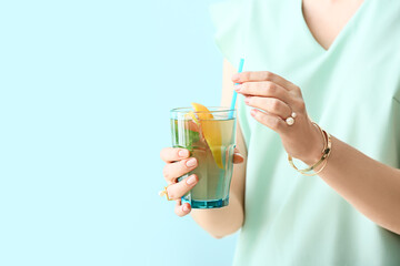 Woman with glass of tasty grapefruit lemonade on color background