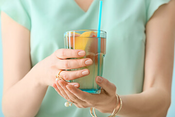 Woman with glass of tasty grapefruit lemonade, closeup