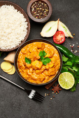 Plate of Traditional Chicken Curry and spices on dark concrete background