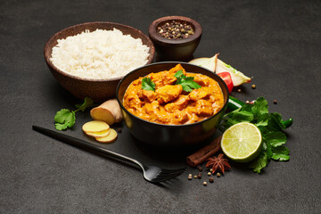 Plate of Traditional Chicken Curry and spices on dark concrete background