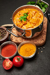 Pot of Traditional Chicken Curry and spices on cork serving board