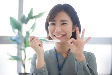 歯ブラシを持ち手でマルを作る女性社員