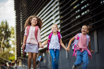 Smiling kids going back home after school. The school girls running  in school yard.