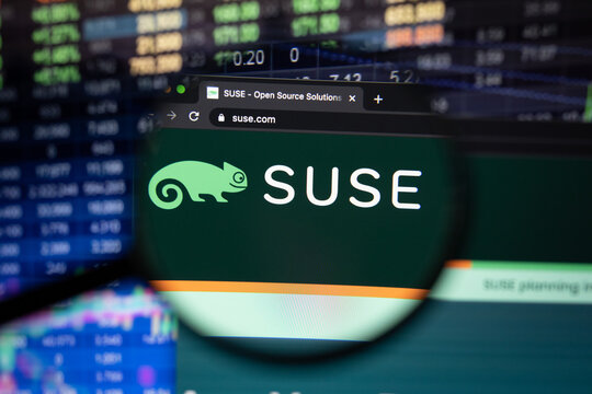 Suse company logo on a website with blurry stock market developments in the background, seen on a computer screen through a magnifying glass