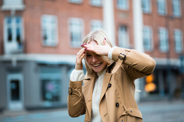 Fototapeta premium Yong happy woman on the street. Girl hiding her face with hands.