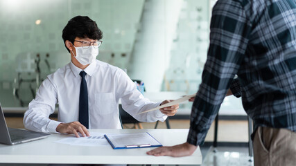 Covid-19 concept two businessmen wearing a mask planning for new project during Coronavirus outbreak (COVID-19)