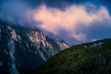Dramatic sky over Dolina Roztoki Valley, High Tatra Mountains, Poland. Sunset illuminating the clouds and rocky formations. Selective focus on the pine forest, blurred background.