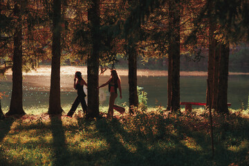 Pair of hippie women walk hand in hand in the forest