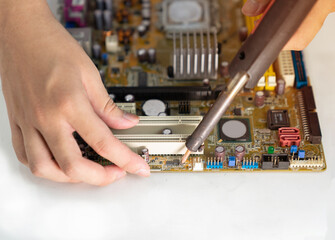 Fototapeta na wymiar Close up of a man hands use electric soldering iron repairing computer