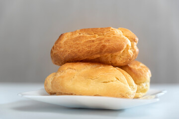 Profiteroles on white side view plate. Homemade puffs, popovers, eclairs