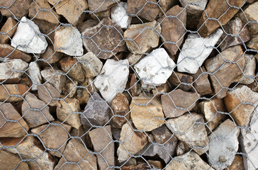 Stones in gabion, wire metal twisted mesh with stones, an element of landscape design.