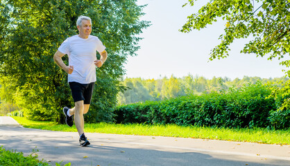 Active mature man running in city park
