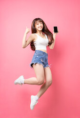 Image of young Asian girl jumping on pink background