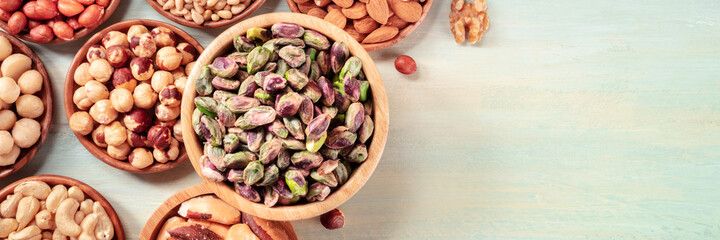 Nuts in wooden bowls panorama, top shot on a rustic background