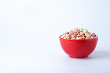 Cereal flakes in red bowl with copy space,Breakfast concept.Food with delicious fruity taste and fruity colours.It's made with maize,wheat,and barley.topview and copy space.white background.