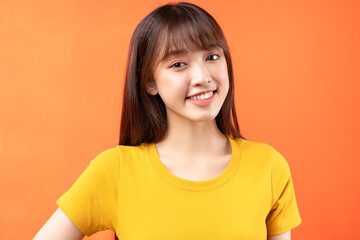 Image of young Asian girl wearing yellow t-shirt on orange background