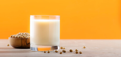Soy milk and soy bean on orange background. Non-dairy milk concept. Vegan Drink. Copy space banner