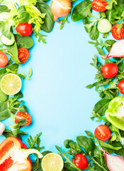 Healthy food frane with various green herbs and vegetables. Ingredients for cooking salad. Vegetarian and vegan food concept. Top view, blue frame with copy space