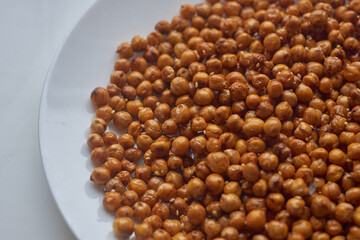 Close-up of roasted chickpeas with sesame seeds on white plate. Delicious vegetarian food, healthy snack. Healthy food concept.