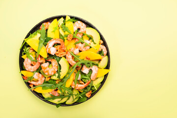 Mango, Shrimps and Avocado Salad with Walnut, Spinach and Arugula. Healthy Eating food concept Top view, lime green background