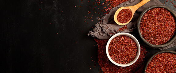 Red quinoa seeds on dark background. Healthy vegan food concept.