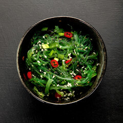 Wakame seaweed with sesame and chilli on gray background. Asian food concept.