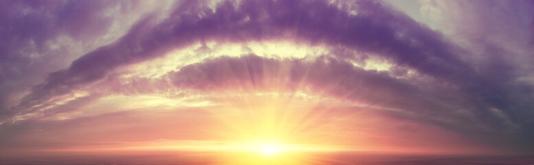 Fantastic panorama of the dramatic cloudy blazing sky in the evening. Clouds in the form of an arch. Colorful cloudy sky at sunset. Gradient color. Sky texture. Abstract nature background