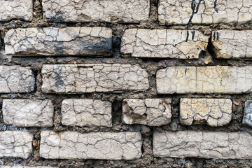 Old brickwork wall. White bricks with many cracks.