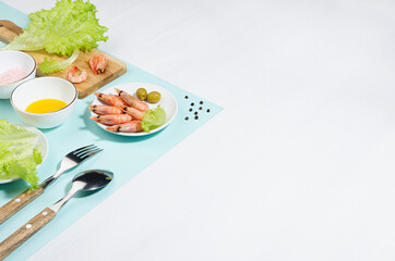 Recipe of organic salad of green salad, shrimps, spice and oil on minty background, copy space. Modern trend concept with shadow and hard light.