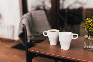 Two cups of coffee on the table on wooden brown terrace during evening sunset