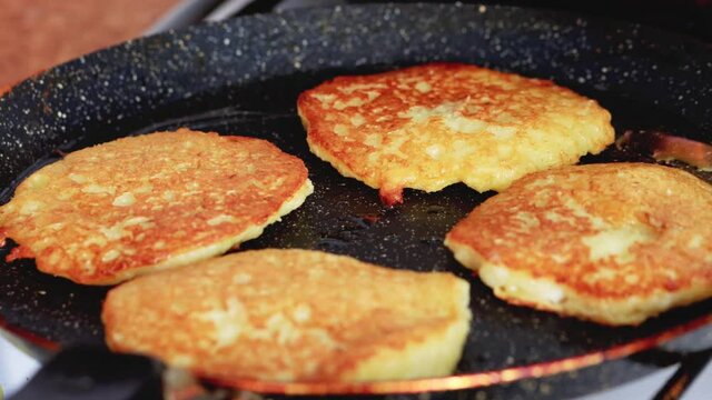 Potato pancakes are fried in a pan, golden crust. Delicious traditional food, macro.
