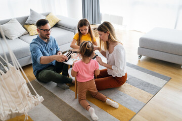 Happy young parents and children having fun, playing board game at home