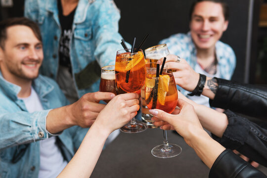 Friends Celebrating And Holding Glasses With Different Alcohol Drinks In A Bar.