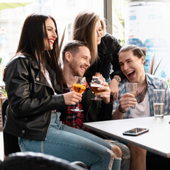 Group of friends are drinking beer and cocktails in a bar