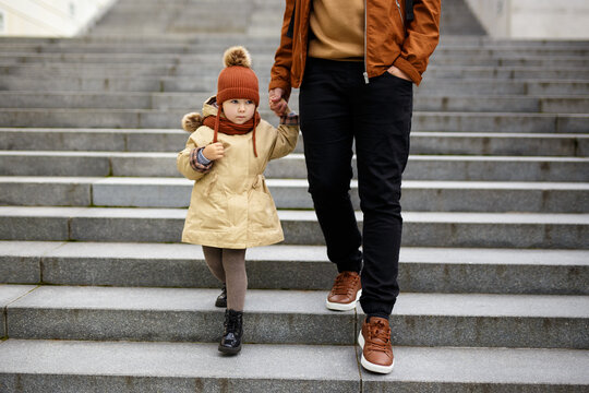 family and love concept - father and cute little girl going down the stairs hand in hand
