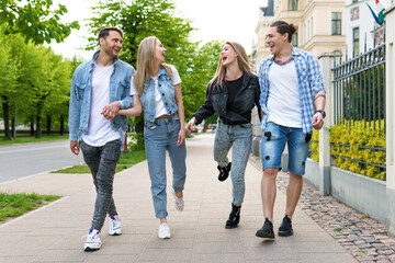 Group of best friends are having fun while walking by city street