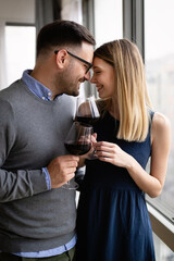 Cheerful happy couple in love drinking wine and having romantic date
