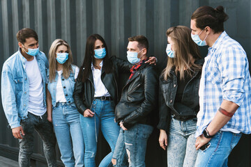 Group of friends wearing prevention masks during their meeting outdoors.