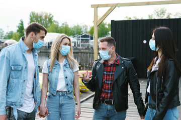 Group of friends wearing prevention masks during their meeting outdoors.